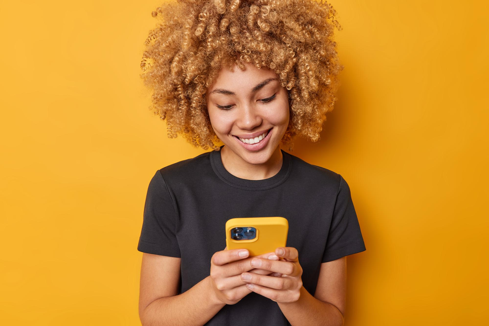 Horecamedewerker controleert haar smartphone, een essentiële tool voor het nauwkeurig bijhouden van urenregistratie en het voorkomen van boetes in de horeca.