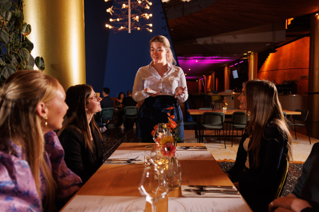 Medewerker van De Harmonie helpt gasten in het restaurant van de schouwburg. Dankzij de koppeling tussen L1NDA en Yesplan loopt de planning soepel en georganiseerd.
